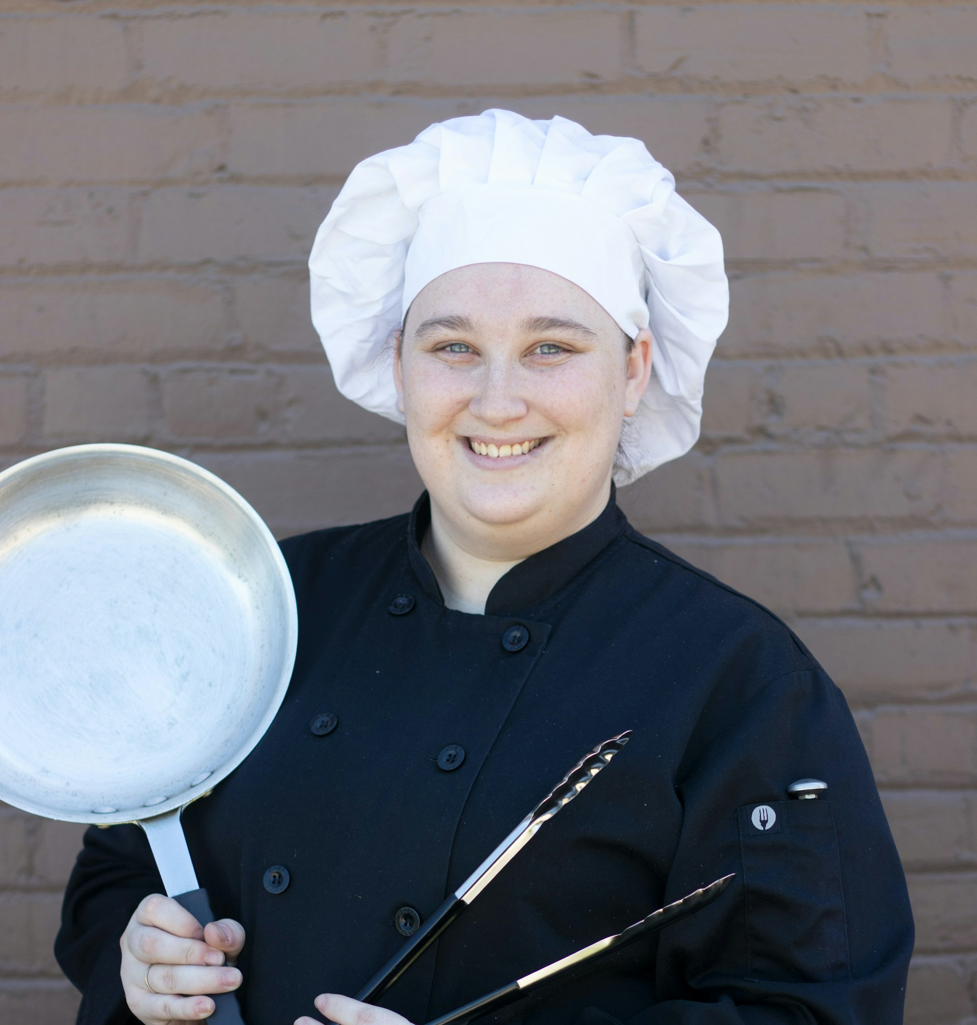 Una chef donna che tiene in mano utensili da cucina