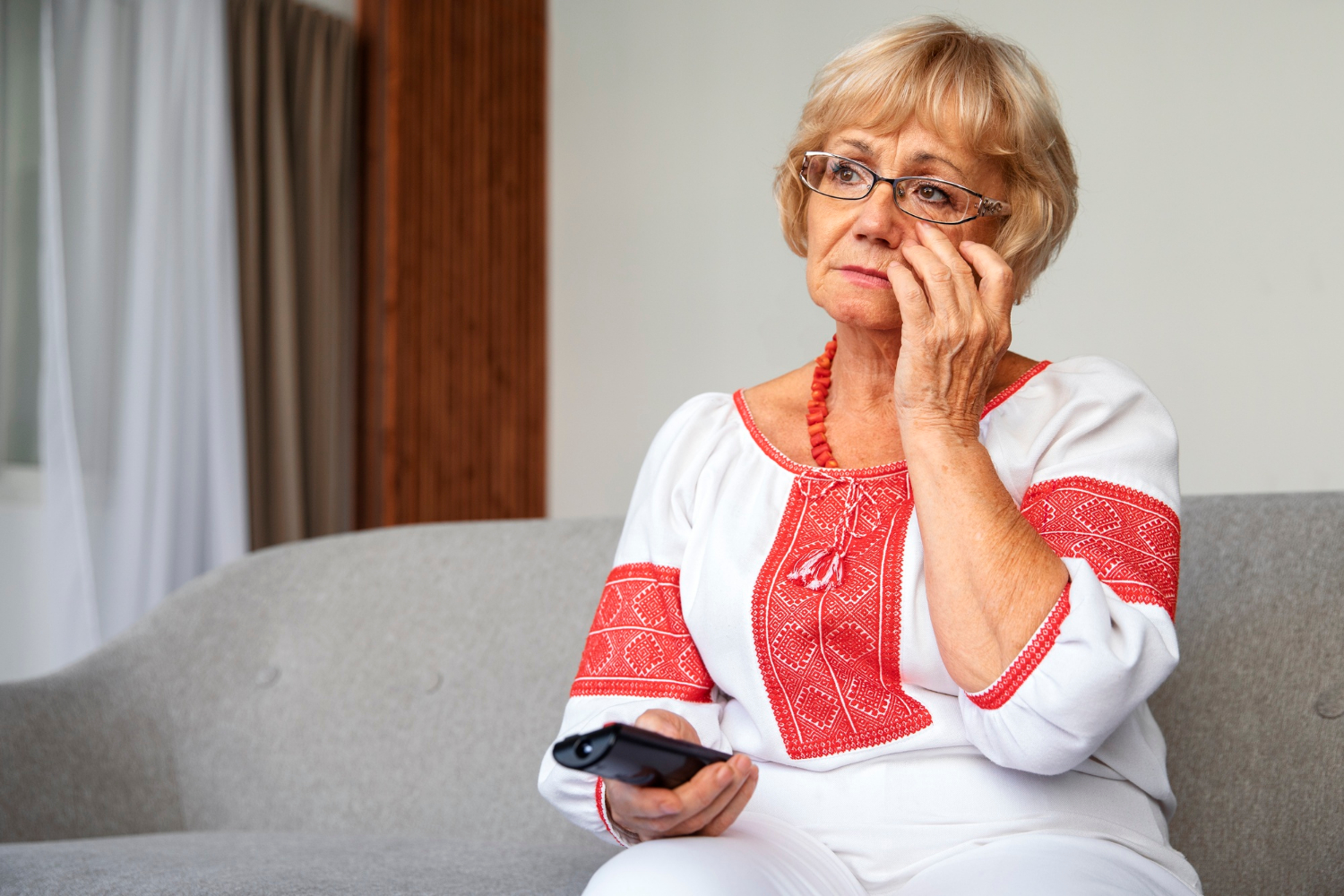 Una donna anziana triste che tiene in mano il telecomando | Fonte: Freepik